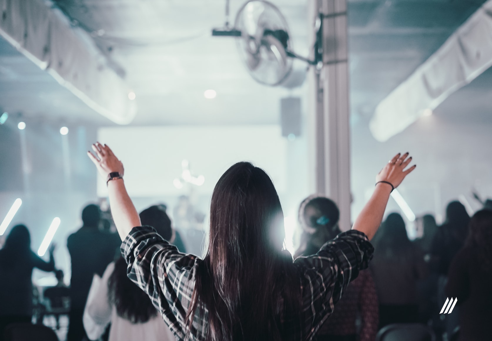 A woman at a church service in Philadelphia raising her arms in prayer at an Evangelical Christian song.